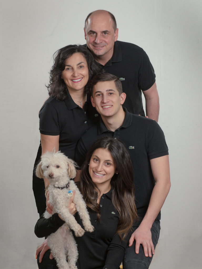 Family portrrat in studio with their pet dog, a white poodle